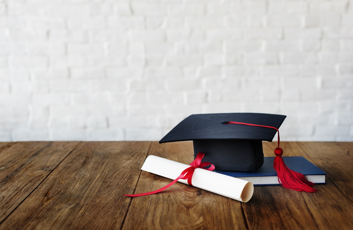un diplôme du brevet sur une table avec un chapeau et un livre