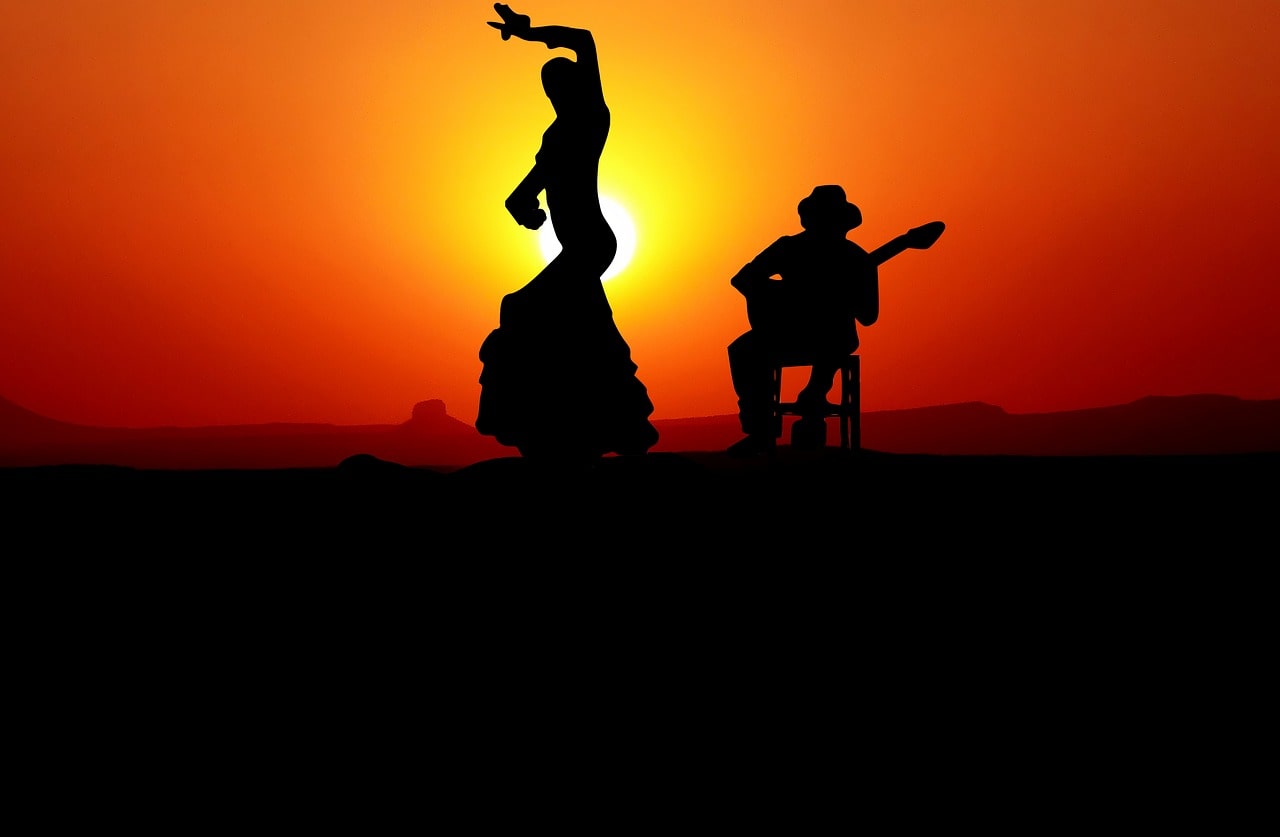 une danseuse espagnole de Flamenco ainsi qu'un joueur de guitare espagnole devant un couché de soleil