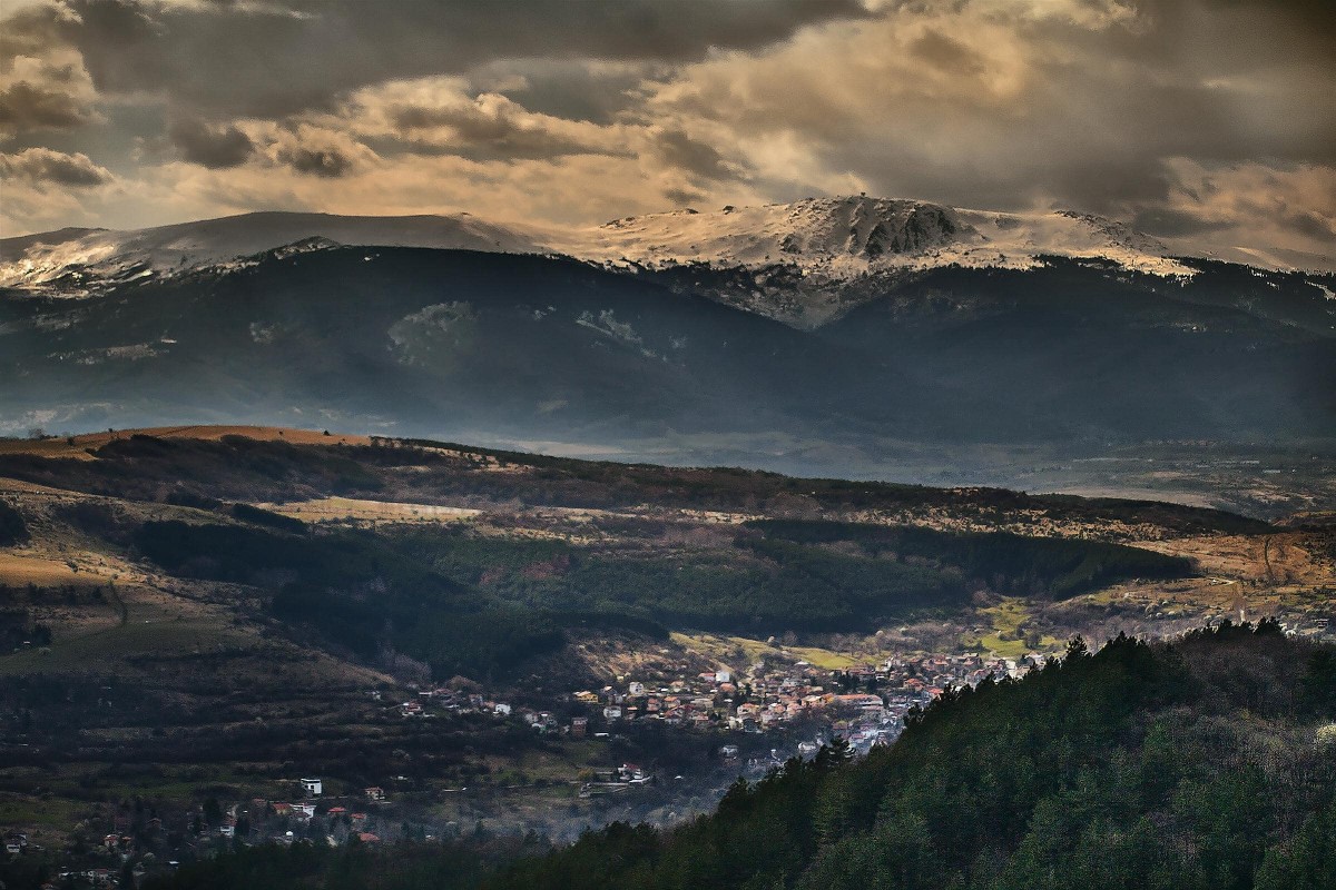 un petit village logé dans une vallée boisée entre deux montagnes